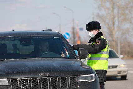 Красноярск. Сотрудник ДПС проверяет документы у водителя на въезде в город в связи с введением дополнительных ограничений из-за распространения коронавируса COVID-19.