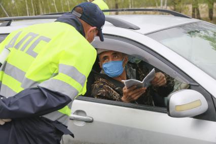 Барнаул. Сотрудник ДПС останавливает водителя для проверки пропуска на выезде из города. С 1 мая действует пропускной режим в связи с введением ограничений из-за распространения COVID-19.
