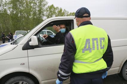 Барнаул. Сотрудник ДПС останавливает водителя для проверки пропуска на выезде из города. С 1 мая действует пропускной режим в связи с введением ограничений из-за распространения COVID-19.