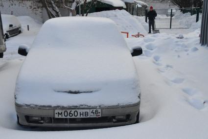 Москва.  Заснеженные автомобили на одной из улиц города.