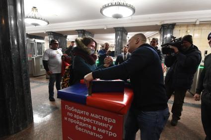 Москва. Пассажирка меряется силами с участником сборной России по силовому экстриму во время проведения праздничной спортивной программы в честь Дня защитника Отечества на станции метро `Курская`.