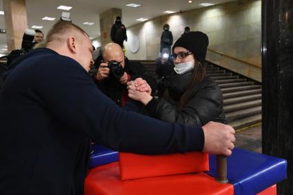 Москва. Пассажирка меряется силами с участником сборной России по силовому экстриму во время проведения праздничной спортивной программы в честь Дня защитника Отечества на станции метро `Курская`.