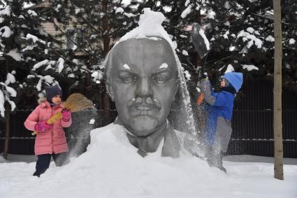 Московская область. Девочки очищают памятник Ленину от снега.