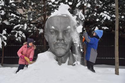 Московская область. Девочки очищают памятник Ленину от снега.