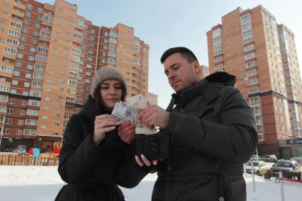 Иркутск.  Молодой человек с девушкой считают деньги в кошельке.