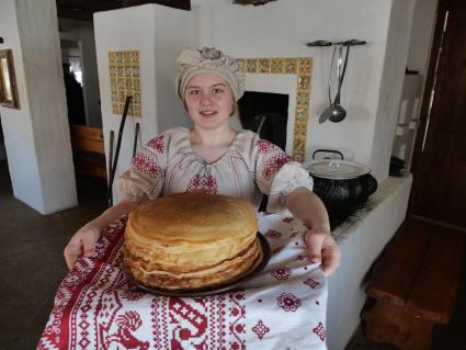 Ульяновск. Девушка в русском национальном костюме держит тарелку с блинами.