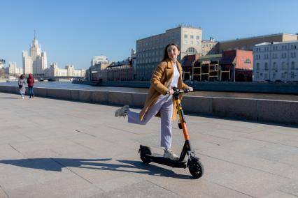 Москва.  Девушка с электросамокатом на Москворецкой набережной.