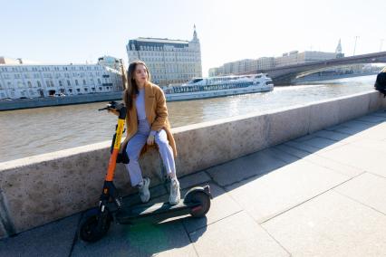 Москва.  Девушка с электросамокатом на Москворецкой набережной.