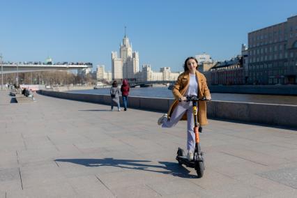 Москва.  Девушка с электросамокатом на Москворецкой набережной.