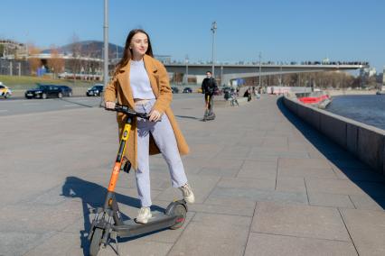 Москва.  Девушка с электросамокатом на Москворецкой набережной.