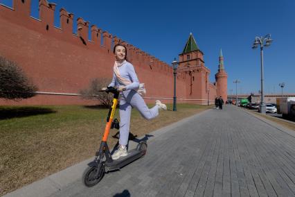 Москва. Девушка с электросамокатом на Кремлевской набережной.