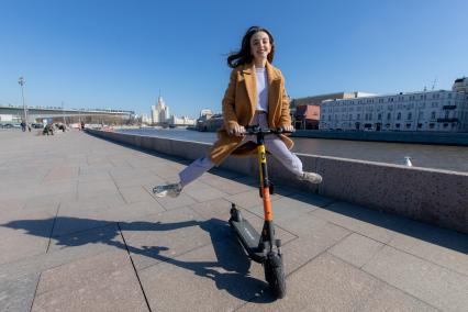 Москва.  Девушка с электросамокатом на Москворецкой набережной.