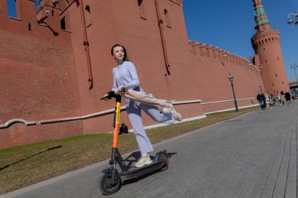 Москва. Девушка с электросамокатом на Кремлевской набережной.