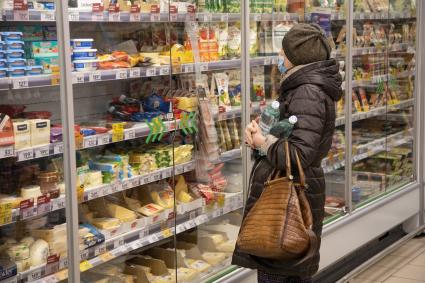 Пермь. Женщина стоит у витрины с молочными продуктами в магазине `Пятерочка`.