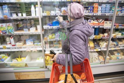 Пермь. Женщина стоит у витрины с молочными продуктами в магазине `Пятерочка`.