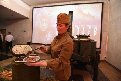 Москва. ММКФ. Девушка в военной форме периода Великой отечественной войны угощает кашей перед премьерой фильма `Девятаев` в кинотеатре `Поклонка`.