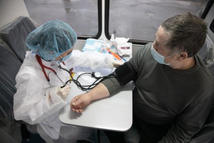 Пермь. Врач проводит осмотр мужчины перед вакцинацией от коронавирусной инфекции в мобильном  пункте вакцинации.