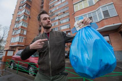 Москва. Корреспондент `Комсомольской правды` Андрей Абрамов держит в руке пакет с мусором и деньги.