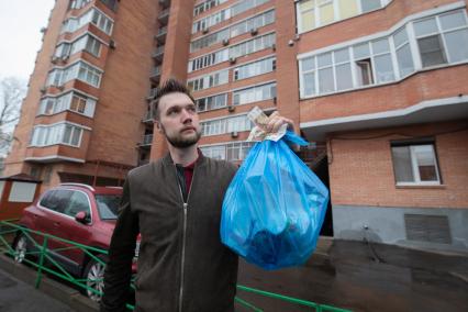 Москва. Корреспондент `Комсомольской правды` Андрей Абрамов держит в руке пакет с мусором и деньги.