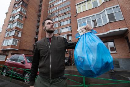 Москва. Корреспондент `Комсомольской правды` Андрей Абрамов держит в руке пакет с мусором и деньги.