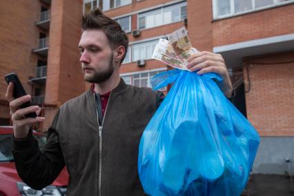 Москва. Корреспондент `Комсомольской правды` Андрей Абрамов держит в руке пакет с мусором и деньги.