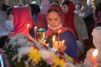 Пермь.  Женщина  ставит свечи во время пасхальной службы в храме.