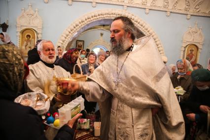 Красноярск. Прихожане и священнослужитель во время освящения пасхальных куличей и яиц в Покровском кафедральном соборе.