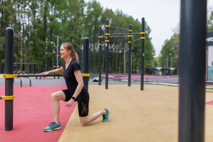 Москва. Девушка занимается фитнесом на спортивной площадке в парке.