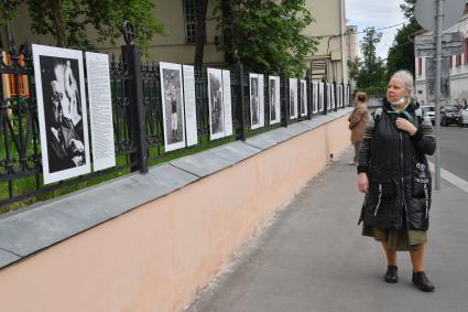 Москва.  Прохожие у фотографий  на выставке под открытым небом -  проект `Люди` журналиста и фотографа Юрия Роста , у храма Живоначальной Троицы в Хохлах .