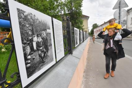 Москва.  Прохожие у фотографий  на выставке под открытым небом -  проект `Люди` журналиста и фотографа Юрия Роста , у храма Живоначальной Троицы в Хохлах .