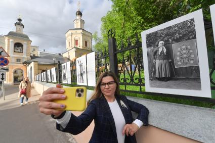 Москва.  Прохожие у фотографий  на выставке под открытым небом -  проект `Люди` журналиста и фотографа Юрия Роста , у храма Живоначальной Троицы в Хохлах .