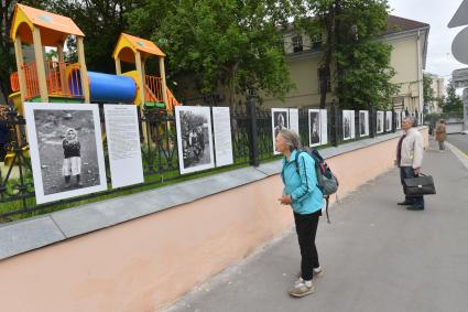 Москва.  Прохожие у фотографий  на выставке под открытым небом -  проект `Люди` журналиста и фотографа Юрия Роста , у храма Живоначальной Троицы в Хохлах .