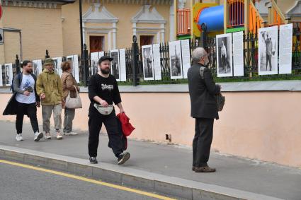 Москва. Прохожие у фотографий на выставке под открытым небом - проект `Люди` журналиста и фотографа Юрия Роста , у храма Живоначальной Троицы в Хохлах .