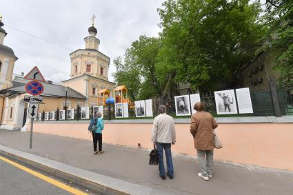 Москва.  Прохожие у фотографий  на выставке под открытым небом -  проект `Люди` журналиста и фотографа Юрия Роста , у храма Живоначальной Троицы в Хохлах .