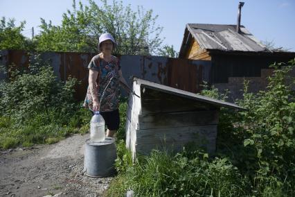 Екатеринбург. Женщина набирает воду на водной колонке в саду