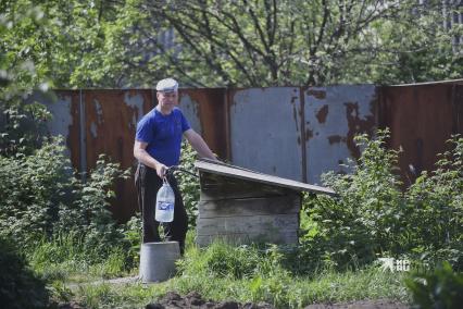 Екатеринбург. Мужчина набирает воду на водной колонке в саду