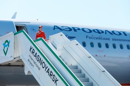 Красноярск. Бортпроводница авиакомпании `Аэрофлот` стоит на трапе самолета Airbus A321neo в аэропорту.