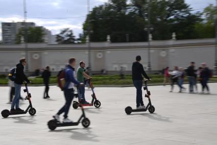 Москва. Молодые люди катаются  на электросамокате  на ВДНХ.