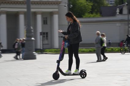 Москва. Девушка едет на электросамокате  на ВДНХ.