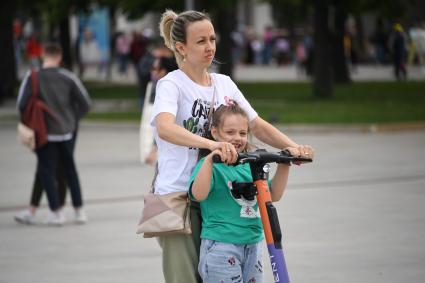 Москва. Женщина с девочкой на самокате.