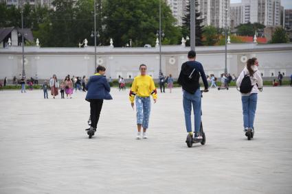 Москва. Молодые люди катаются  на электросамокате  на ВДНХ.