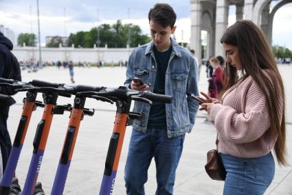 Москва.  Посетители берут самокаты на пункте проката электросамокатов на ВДНХ.