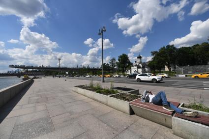 Москва. Мужчина лежит на лавке Москворецкой набережной.