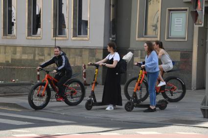 Москва. Горожане на велосипедах и самокатах на улице города.