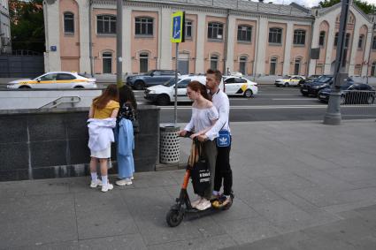 Москва. Молодые люди едут на самокате.