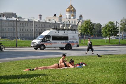 Москва. Горожане загорают на газоне в Парке Музеон.