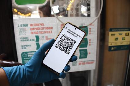 Москва. Сотрудница кафе проверяет QR-код у посетителей на входе в заведение.