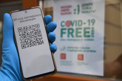 Москва. Сотрудница кафе проверяет QR-код у посетителей на входе в заведение.