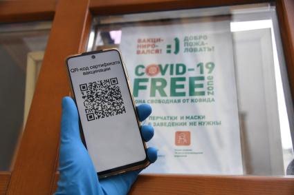 Москва. Сотрудница кафе проверяет QR-код у посетителей на входе в заведение.