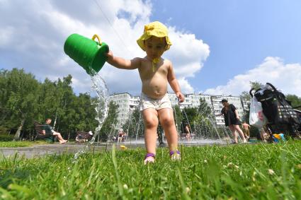 Москва. Девочка выливает воду из ведерка на газон.